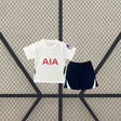 Equipación Tottenham 26-27 local niño vista frontal con camiseta blanca y pantalón corto azul marino con paneles laterales blancos