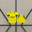 Equipación Villarreal 26-27 local niño vista frontal con camiseta amarilla de cuello en pico y pantalón corto amarillo con detalles oscuros