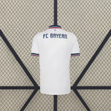 Segunda vista trasera de la camiseta Bayern Munich 26-27 visitante, con espalda blanca lisa, cuello tipo polo azul y detalles en contraste