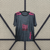 Vista frontal alternativa de la camiseta Malaga 26-27 tercera equipación con base oscura, detalles rosas en hombros y estampado tonal