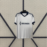 Vista frontal alternativa de la camiseta Schalke 26-27 visitante blanca con cuello azul marino, manga corta y detalles oscuros en hombros
