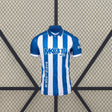 Vista frontal de la camiseta Alavés 26-27 local con franjas verticales azules y blancas, cuello tipo polo azul y manga corta