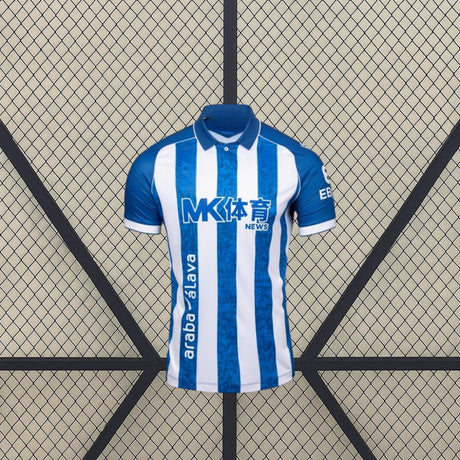 Vista frontal de la camiseta Alavés 26-27 local con franjas verticales azules y blancas, cuello tipo polo azul y manga corta