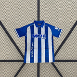 Vista frontal de la camiseta Alavés 26-27 local extendida, con diseño de rayas verticales azules y blancas y cuello polo azul