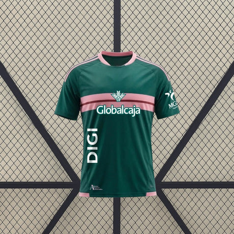 Vista frontal de la camiseta Albacete 26-27 Visitante verde con franja rosa en el pecho, detalles rosas en hombros y cuello redondo
