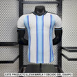 Vista frontal de la camiseta Argentina 26-27 local versión Player, blanca con franjas celestes degradadas, cuello negro y manga corta