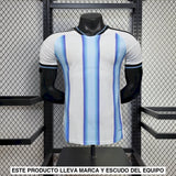 Vista frontal de la camiseta Argentina 26-27 local versión Player, blanca con franjas celestes degradadas, cuello negro y manga corta