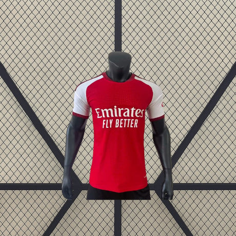 Vista frontal de la camiseta Arsenal 26-27 Local Player Version roja con mangas blancas, cuello redondo y corte ceñido