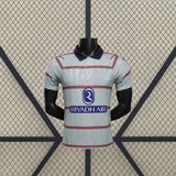 Vista frontal de la camiseta Atlético de Madrid 26-27 3ª equipación Player Version gris verdosa con franjas horizontales y cuello azul marino
