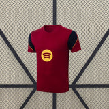 Vista frontal de la camiseta Barcelona 26-27 de entrenamiento en granate con paneles azul marino y detalles amarillos en los hombros