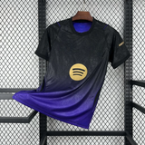 Vista frontal de la camiseta Barcelona 26-27 visitante en negro y morado, con degradado inferior, cuello redondo y detalles dorados