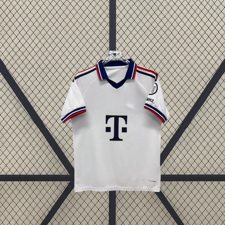 Vista frontal de la camiseta Bayern Munich 26-27 visitante en blanco, con cuello tipo polo, abertura en V y ribetes azules y rojos