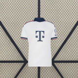 Vista frontal de la camiseta Bayern Munich 26-27 visitante en color blanco, con cuello azul marino y ribetes rojos y azules en mangas y hombros