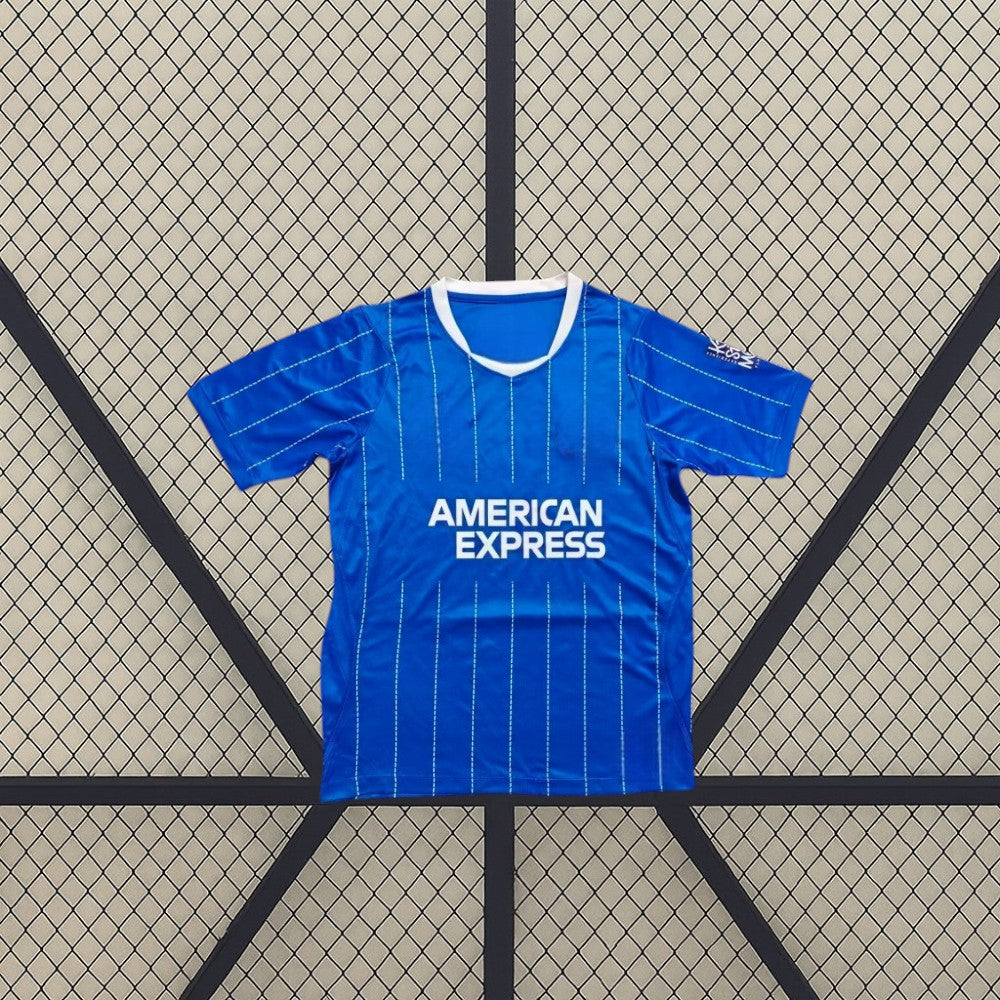 Vista frontal de la camiseta Brighton 26-27 Local azul con finas líneas verticales, mangas cortas y cuello redondo con borde blanco