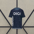 Vista frontal de la camiseta Cádiz 26-27 visitante en azul marino, con estampado tonal, cuello celeste y mangas cortas oscuras