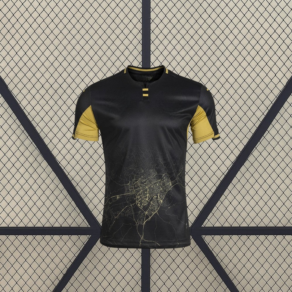 Vista frontal de la camiseta Córdoba 26-27 Visitante negra con mangas doradas, cuello contrastado y gráfico cartográfico en la zona inferior