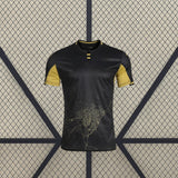 Vista frontal de la camiseta Córdoba 26-27 Visitante negra con mangas doradas, cuello contrastado y gráfico cartográfico en la zona inferior