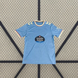 Vista frontal de la camiseta Celta de Vigo 26-27 local extendida, con base azul celeste y sutil patrón vertical tonal