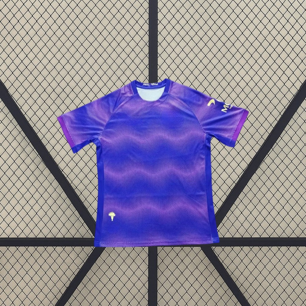 Vista frontal de la camiseta Elche 26-27 Visitante en azul y violeta con patrón gráfico ondulado, cuello redondo y manga corta