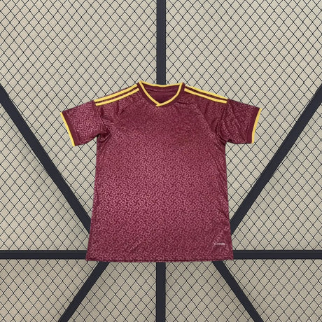 Vista frontal de la camiseta España 26-27 edición especial campeones 2026 granate con patrón tonal, detalles dorados y dos estrellas de bicampeones