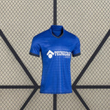 Vista frontal de la camiseta Getafe 26-27 local en color azul, con cuello en pico oscuro, manga corta y patrón tonal en la parte delantera