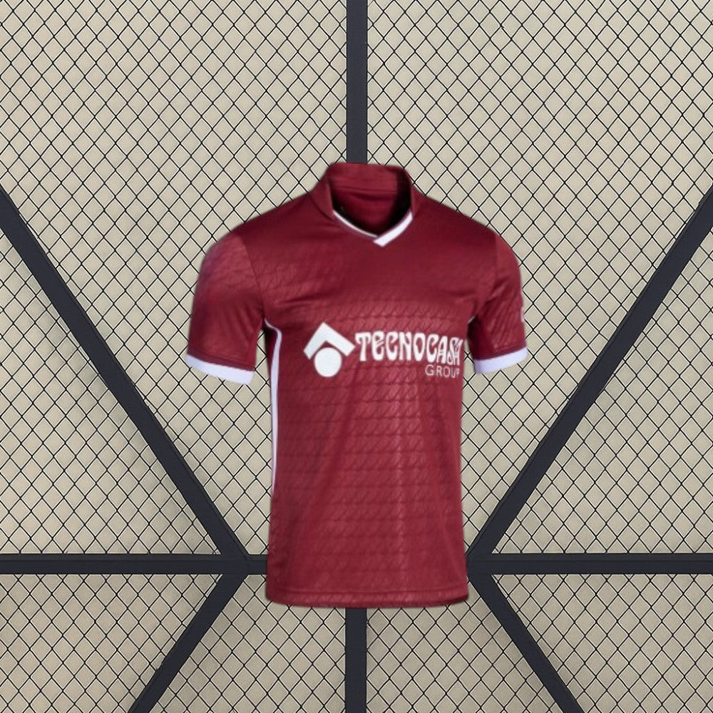 Vista frontal de la camiseta Getafe 26-27 visitante en color granate, con cuello en pico, puños blancos y patrón tonal geométrico