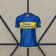 Vista frontal de la camiseta Las Palmas 26-27 visitante en azul, con banda amarilla horizontal, cuello redondo y manga corta