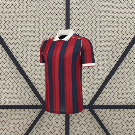 Vista frontal de la camiseta Levante UD 26-27 Local con franjas rojas y azul marino, cuello tipo polo blanco y manga corta