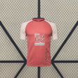 Vista frontal de la camiseta Málaga 26-27 visitante en color coral, con mangas crema, cuello oscuro y textura vertical en el tejido