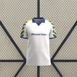Vista frontal de la camiseta Parma 25-26 tercera equipación en blanco, con cuello tipo polo azul y mangas de rayas azules y amarillas