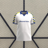 Vista frontal de la camiseta Parma 25-26 tercera equipación en blanco, con cuello tipo polo azul y mangas de rayas azules y amarillas