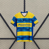 Vista frontal de la camiseta Parma 25-26 visitante en amarillo y azul, con cuello de pico, manga corta y franjas horizontales de efecto difuminado