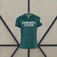 Vista frontal de la camiseta R.M. 26-27 visitante para mujer en verde oscuro, con patrón tonal, manga corta y cuello con abertura