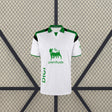 Vista frontal de la camiseta Racing Santander 26-27 local blanca con líneas verticales, cuello verde y paneles negros en los hombros