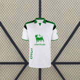 Vista frontal de la camiseta Racing Santander 26-27 local blanca con líneas verticales, cuello verde y paneles negros en los hombros