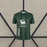 Vista frontal de la camiseta Racing Santander 26-27 visitante en verde oscuro con líneas verticales doradas y cuello tipo polo