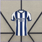 Vista frontal de la camiseta Real Sociedad 26-27 local con franjas verticales blancas y azul marino, cuello redondo y manga corta