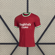 Vista frontal de la camiseta Real Sociedad 26-27 tercera equipación en color rojo con cuello redondo y ribetes verdes y blancos