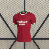 Vista frontal de la camiseta Real Sociedad 26-27 tercera equipación en color rojo con cuello redondo y ribetes verdes y blancos