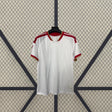 Vista frontal de la camiseta Sevilla 26-27 local en color blanco, con cuello en V, detalles rojos y dorados y textura vertical