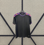 Vista frontal de la camiseta Sevilla 26-27 tercera equipación en negro, con cuello morado, manga corta y franjas rosas y moradas en los hombros