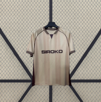 Vista frontal de la camiseta Sporting de Gijón 26-27 3ª equipación en beige con detalles granates, manga corta y franjas verticales tonales