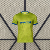 Vista frontal de la camiseta Tenerife 26-27 tercera equipación en amarillo lima con cuello y puños azules y patrón tonal