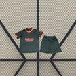 Vista frontal de la equipación AC Milan 26-27 3ª para niño con camiseta verde oscuro, detalles coral y amarillo y pantalón corto a juego