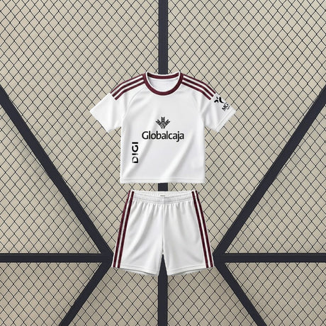 Vista frontal de la equipación Albacete 26-27 Local de niño con camiseta y pantalón blancos y detalles granates