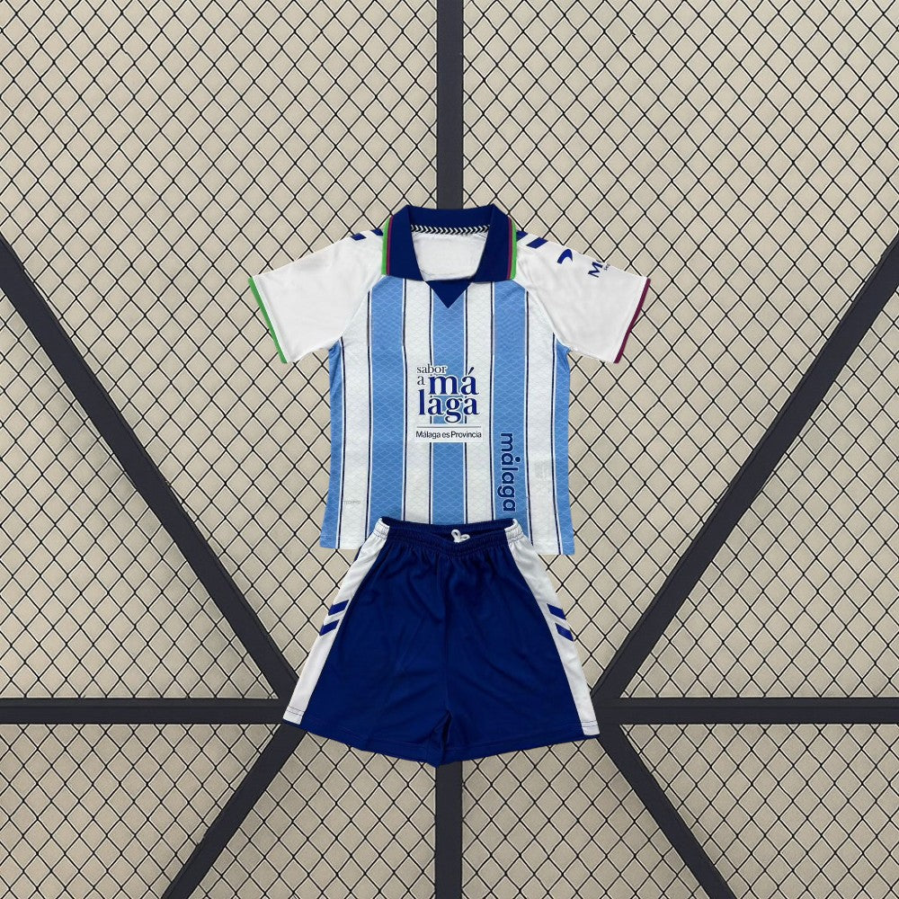 Vista frontal de la equipación Málaga niño 26-27 local con camiseta blanca y azul claro y pantalón azul marino