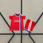 Vista frontal de la equipación Zaragoza 26-27 visitante para niño con camiseta roja, franja vertical blanca y azul y pantalón corto rojo