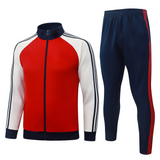 Vista frontal del chándal Arsenal 26-27 Modelo 1 con chaqueta roja de cremallera completa, mangas blancas y pantalón azul marino