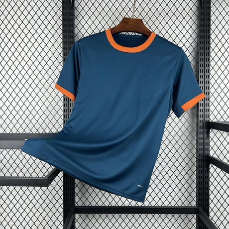 Vista frontal en diagonal de la camiseta Valencia 26-27 visitante en azul oscuro, con cuello redondo y puños naranjas