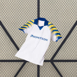 Vista frontal en perspectiva de la camiseta Parma 25-26 tercera equipación, con base blanca y detalle gráfico en las mangas
